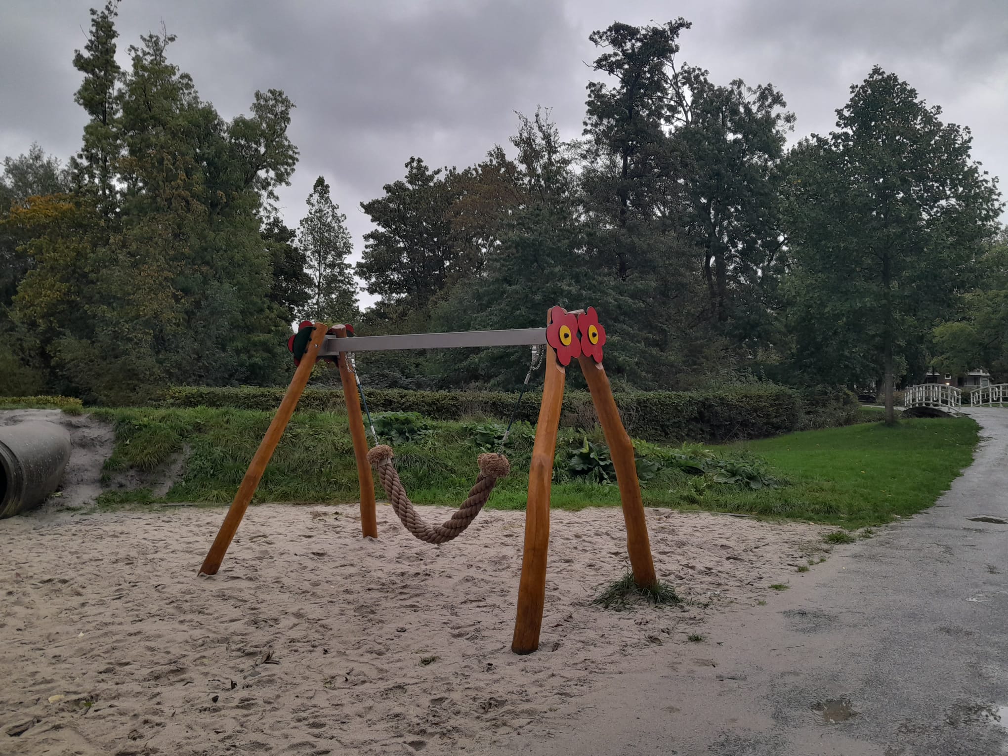 Photo of an empty swing in the sand, with a dark grey sky in the background